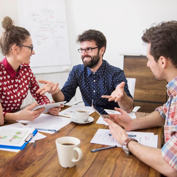 Team Photo of 3 people talking around a table