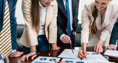 Group Photo of 4 people discussing charts