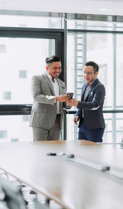 two men in a meeting room smiling at a phone