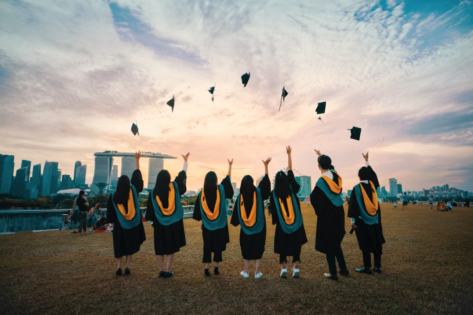 university students throwing their caps into the air together in a line outside