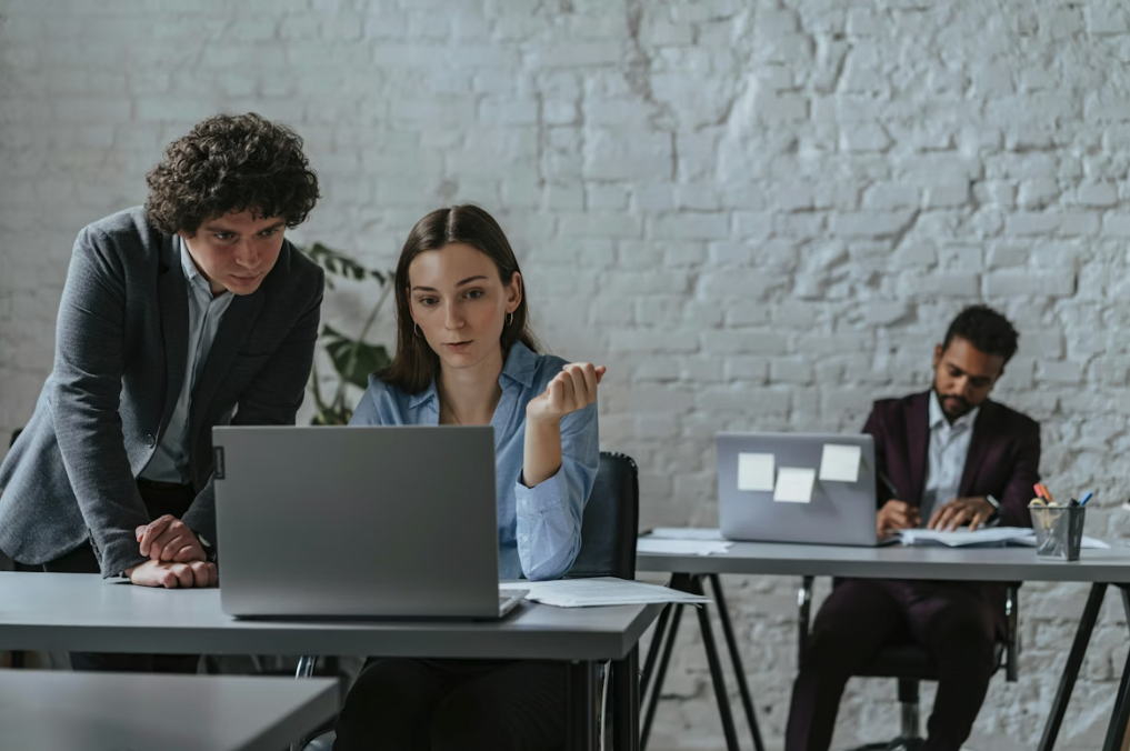 man leaning over a women with a laptop in an office