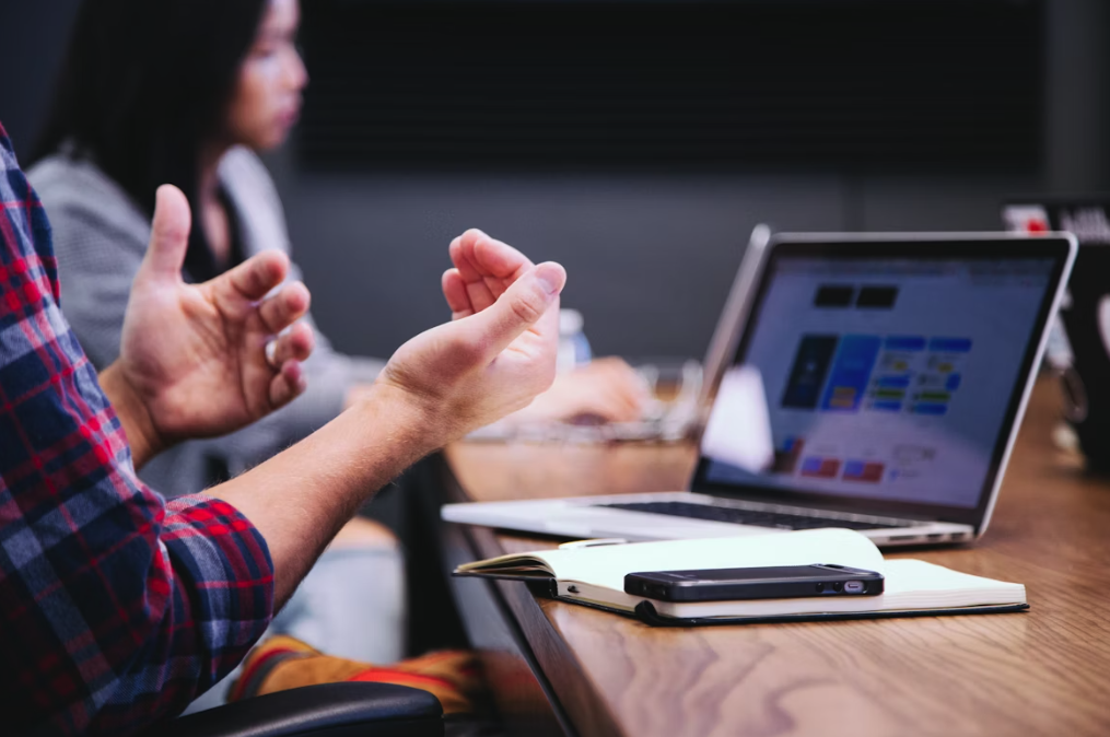 meeting a man using hand gestures with his laptop open on a table
