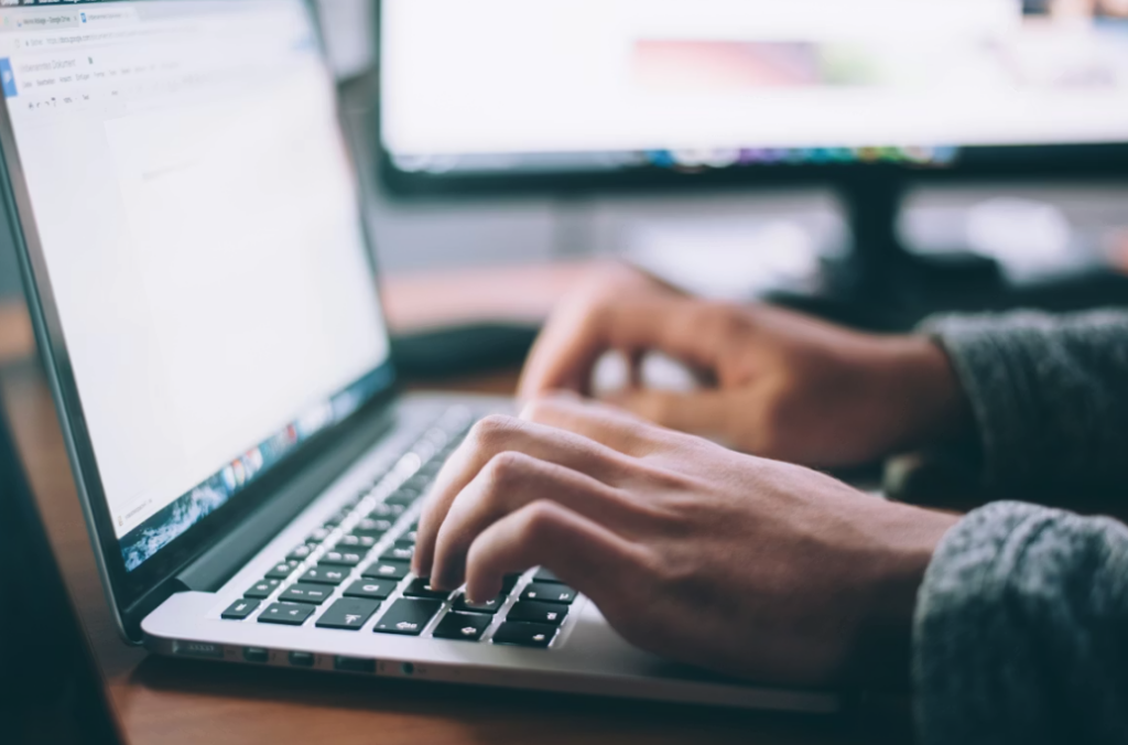 laptop on a desk with hands typing on the keyboard